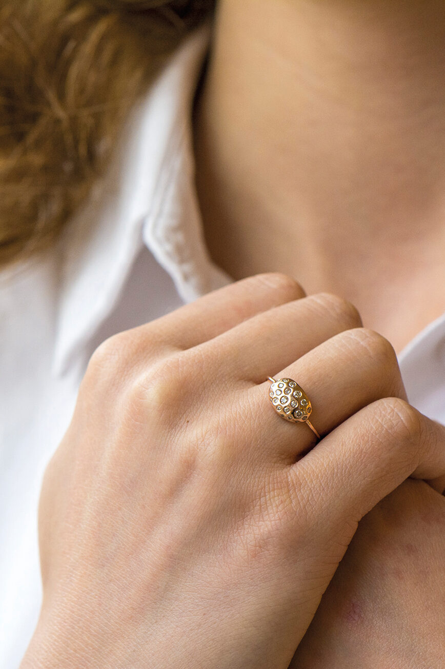 yellow gold ring with an oval dome-shaped shell motif pavé-set with round brilliant diamonds of varying sizes, mounted on a thin band