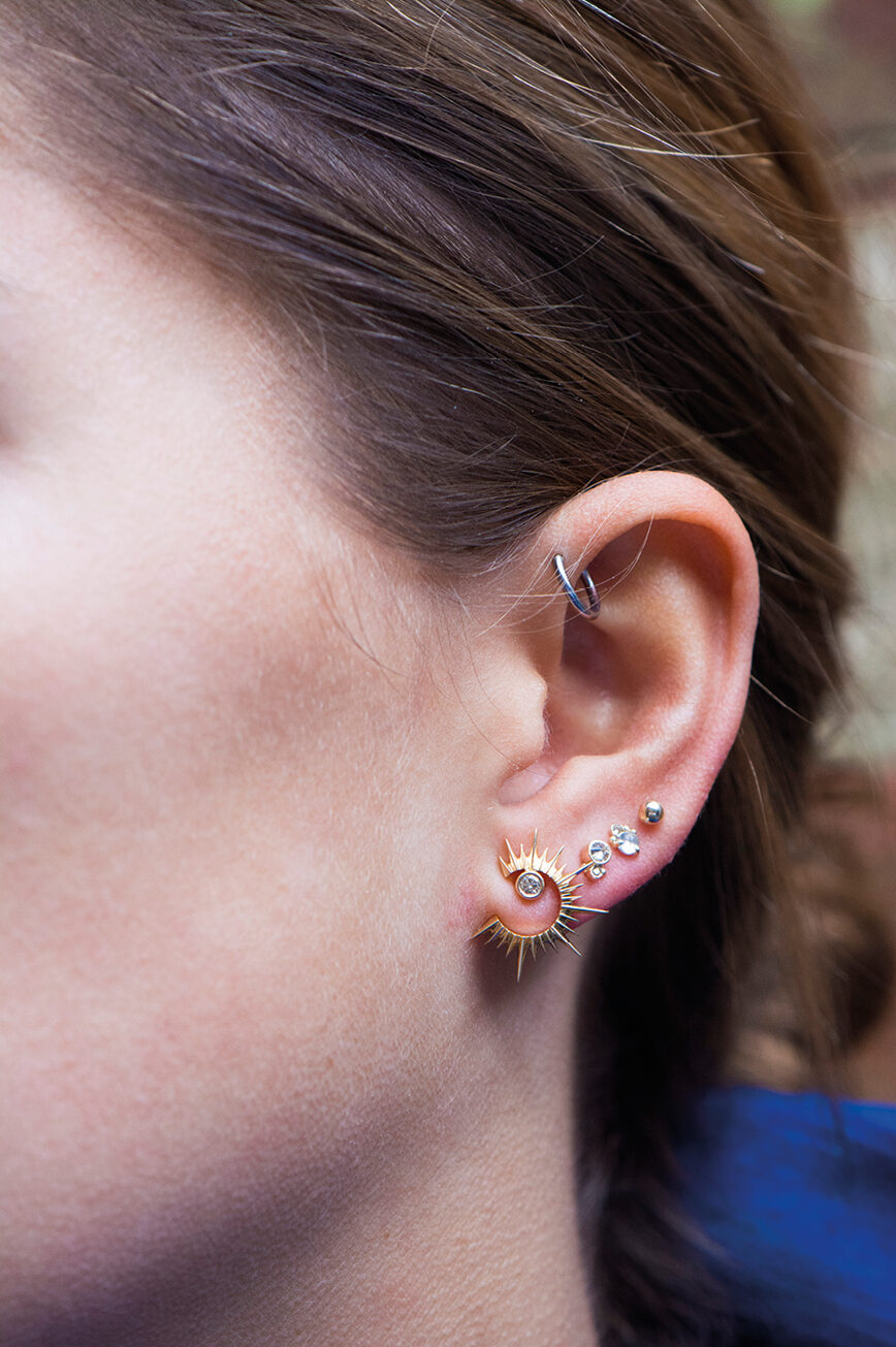 yellow gold statement earrings featuring a circular open sun shape with radiating spikes and a central diamond, creating a bold celestial silhouette