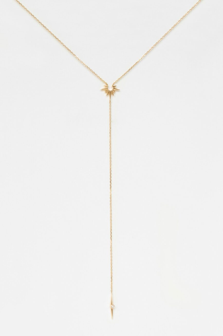 yellow gold lariat necklace with a fine chain ending in a small eight-pointed star pendant set with a round brilliant diamond