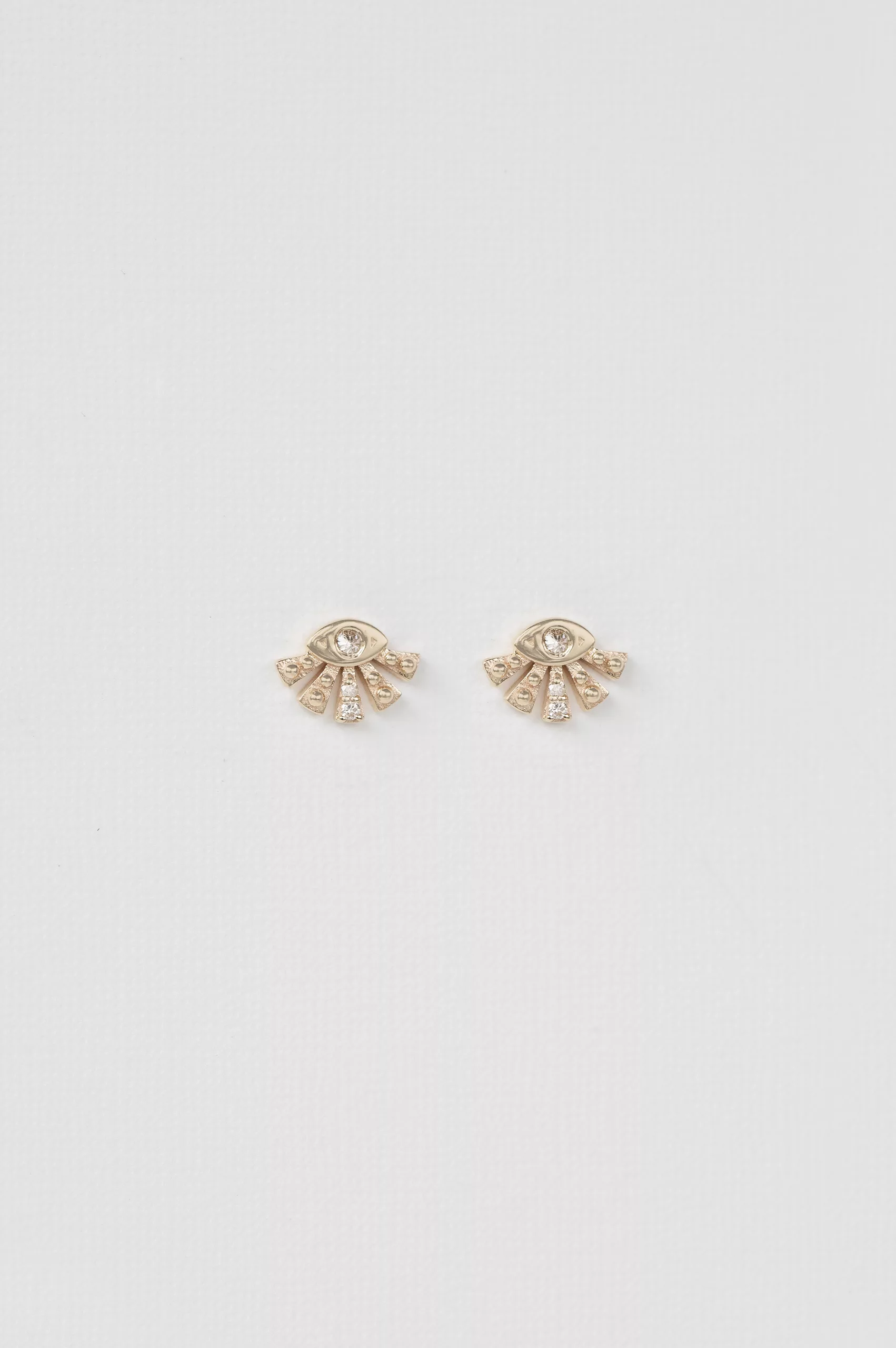 yellow gold stud earrings shaped as a small sunburst fan with a central diamond eye and radiating gold spikes, inspired by Aztec sun motifs