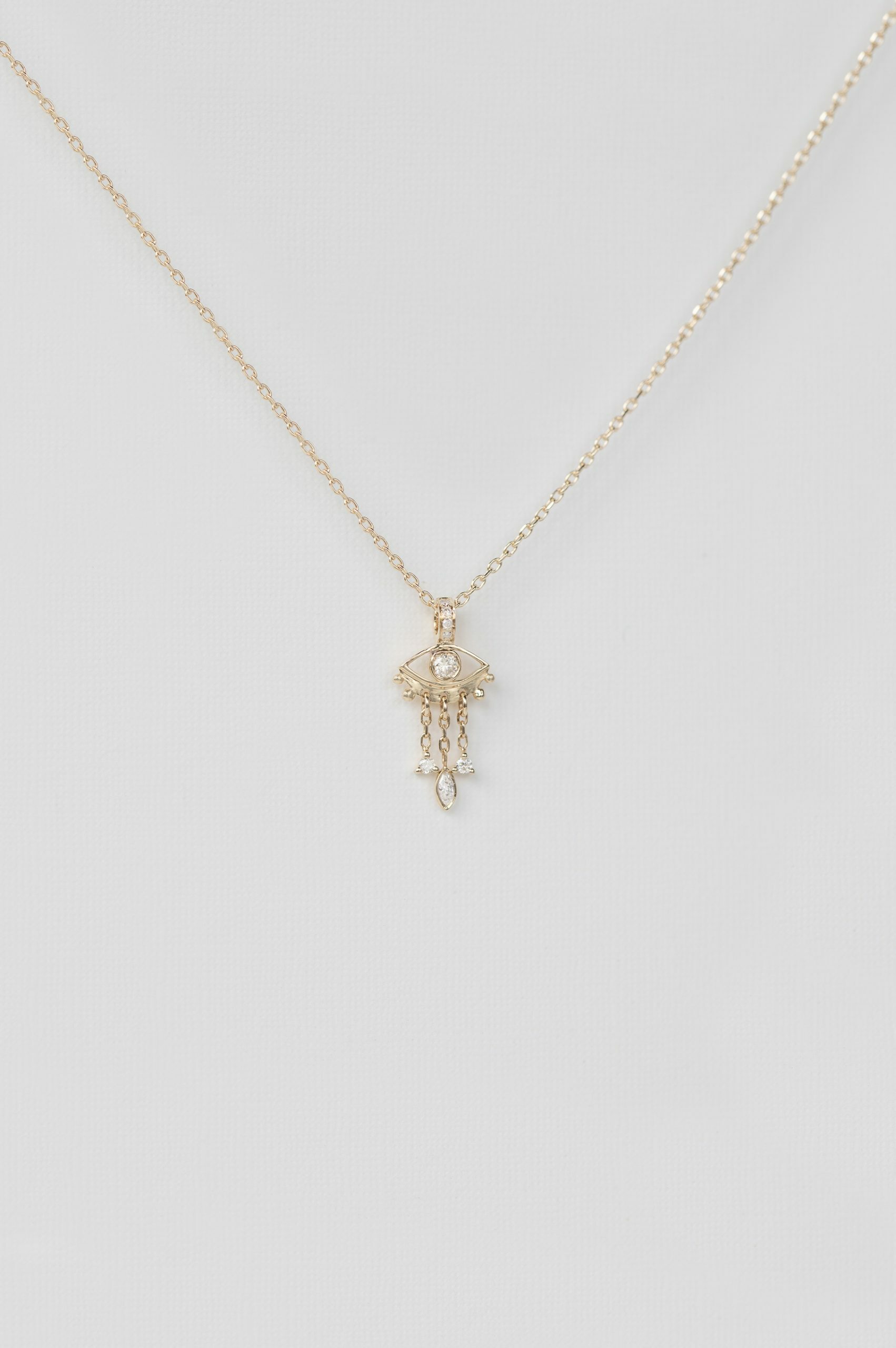 yellow gold necklace with a delicate jellyfish-shaped pendant featuring a central diamond eye and three fine dangling chain drops