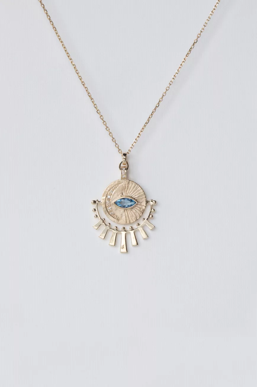 yellow gold necklace with a circular sunburst medal pendant featuring a central marquise aquamarine eye, surrounded by radiating gold sunbeams and small diamond accents