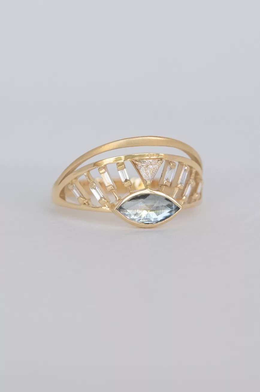 yellow gold architectural ring featuring a marquise-cut aquamarine at center flanked by baguette diamonds, set within an open cage-like crown structure