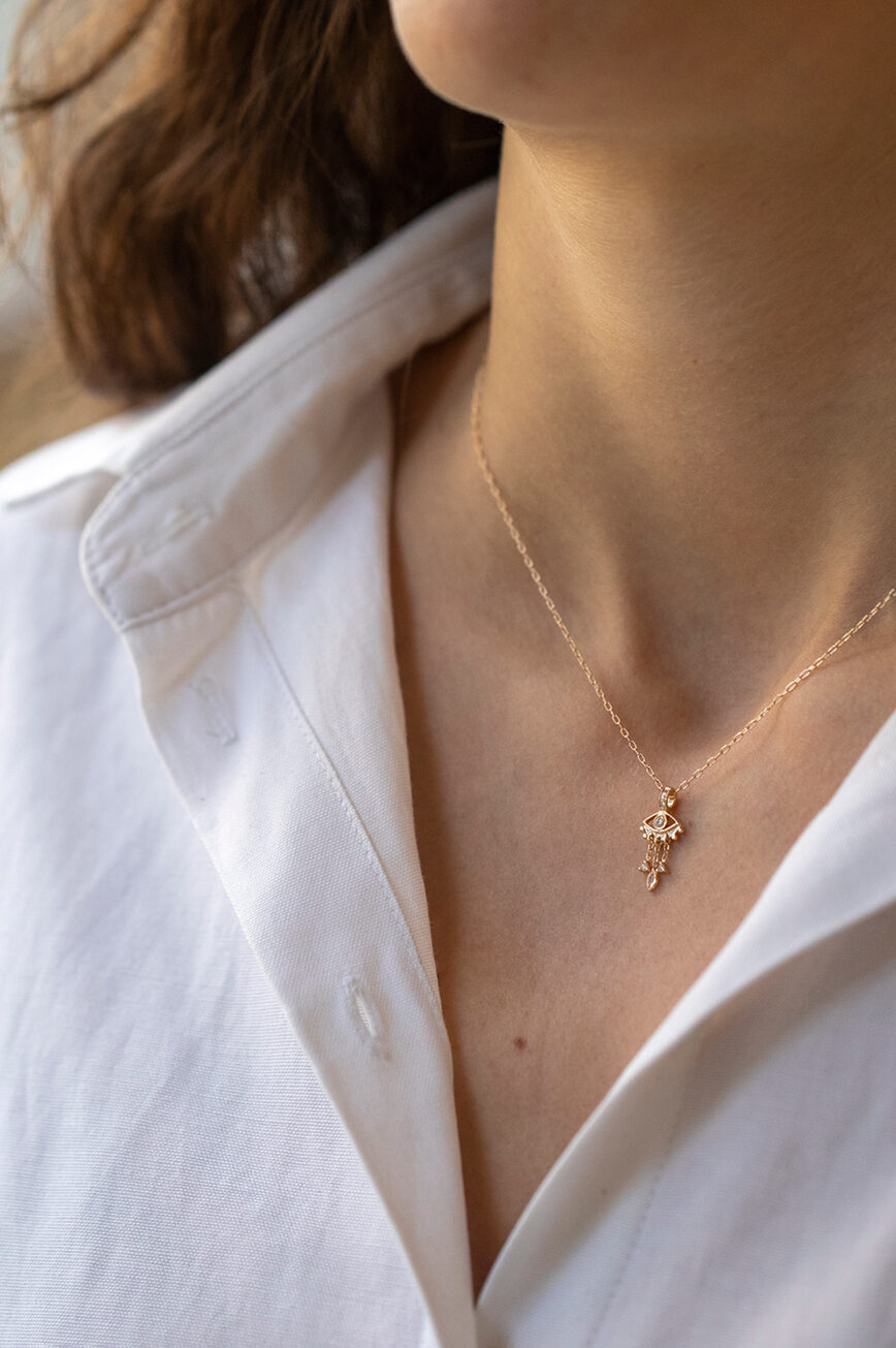 yellow gold necklace with a delicate jellyfish-shaped pendant featuring a central diamond eye and three fine dangling chain drops
