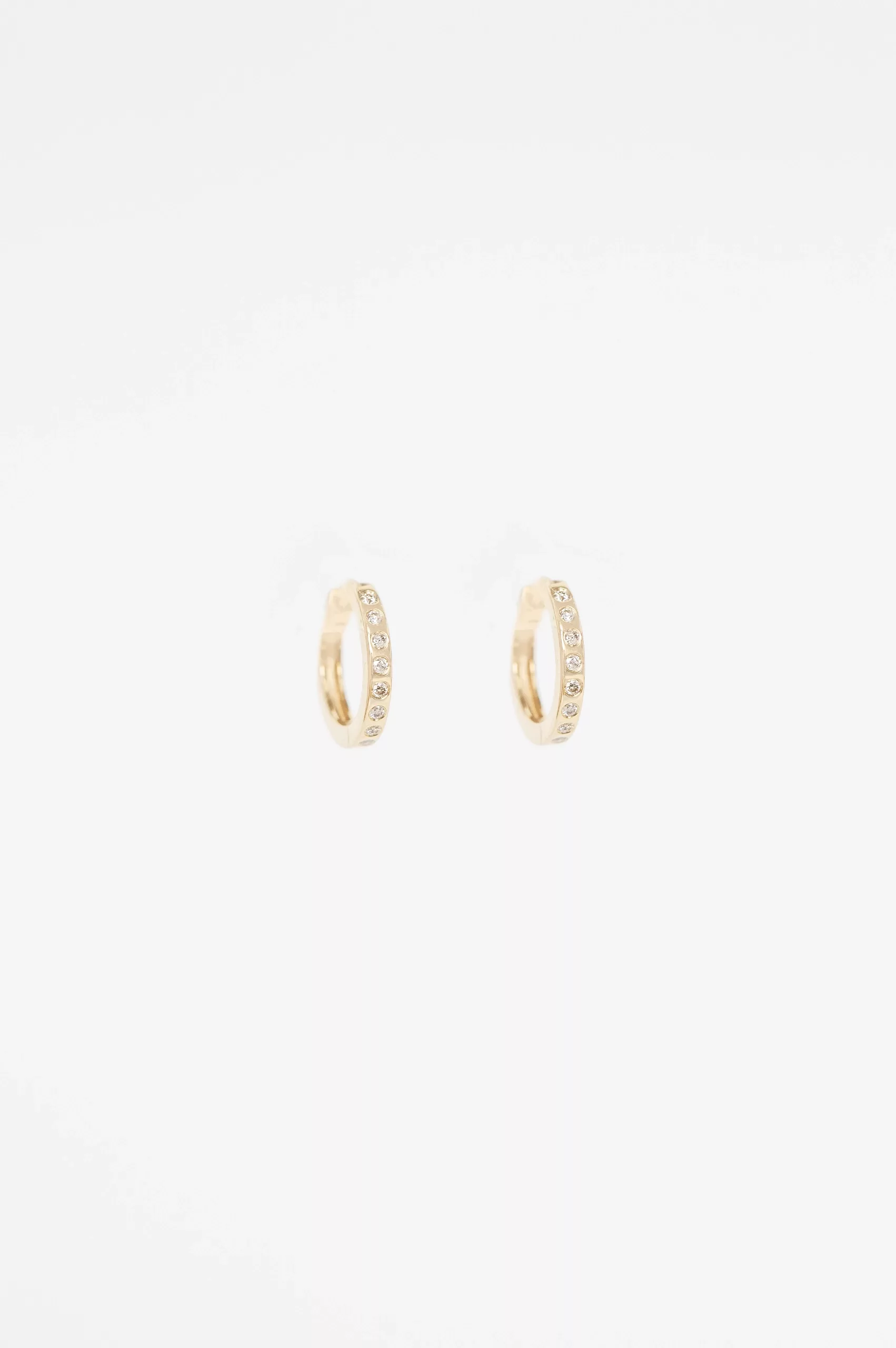 Yellow gold huggie hoop earrings pavé diamond accent worn on ear Celine Daoust