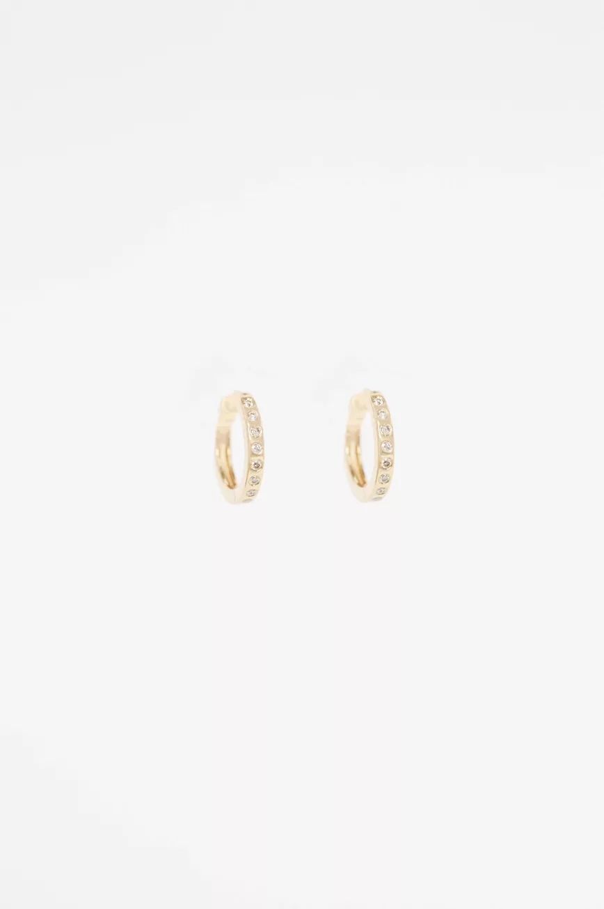 Yellow gold huggie hoop earrings pavé diamond accent worn on ear Celine Daoust