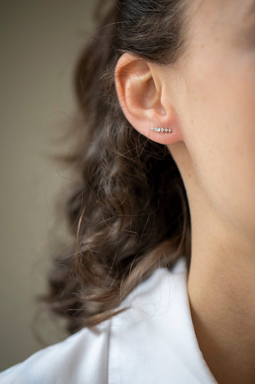 white gold single drop earring featuring a small round moonstone cabochon set in gold with two descending diamond accents, delicate and asymmetric