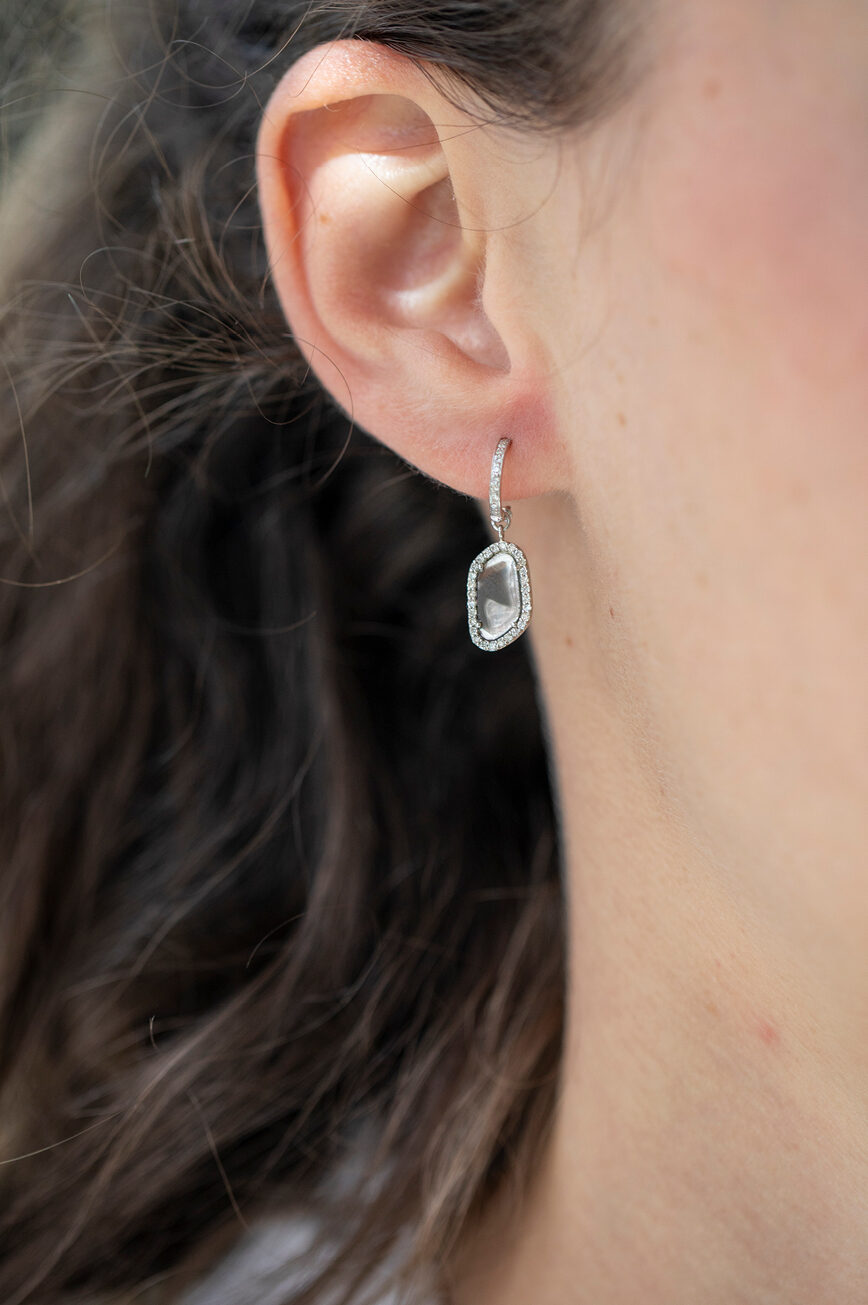 white gold hoop earrings pavé-set with diamonds along the front, each suspending a bezel-set grey diamond in a faceted organic shape surrounded by a diamond halo