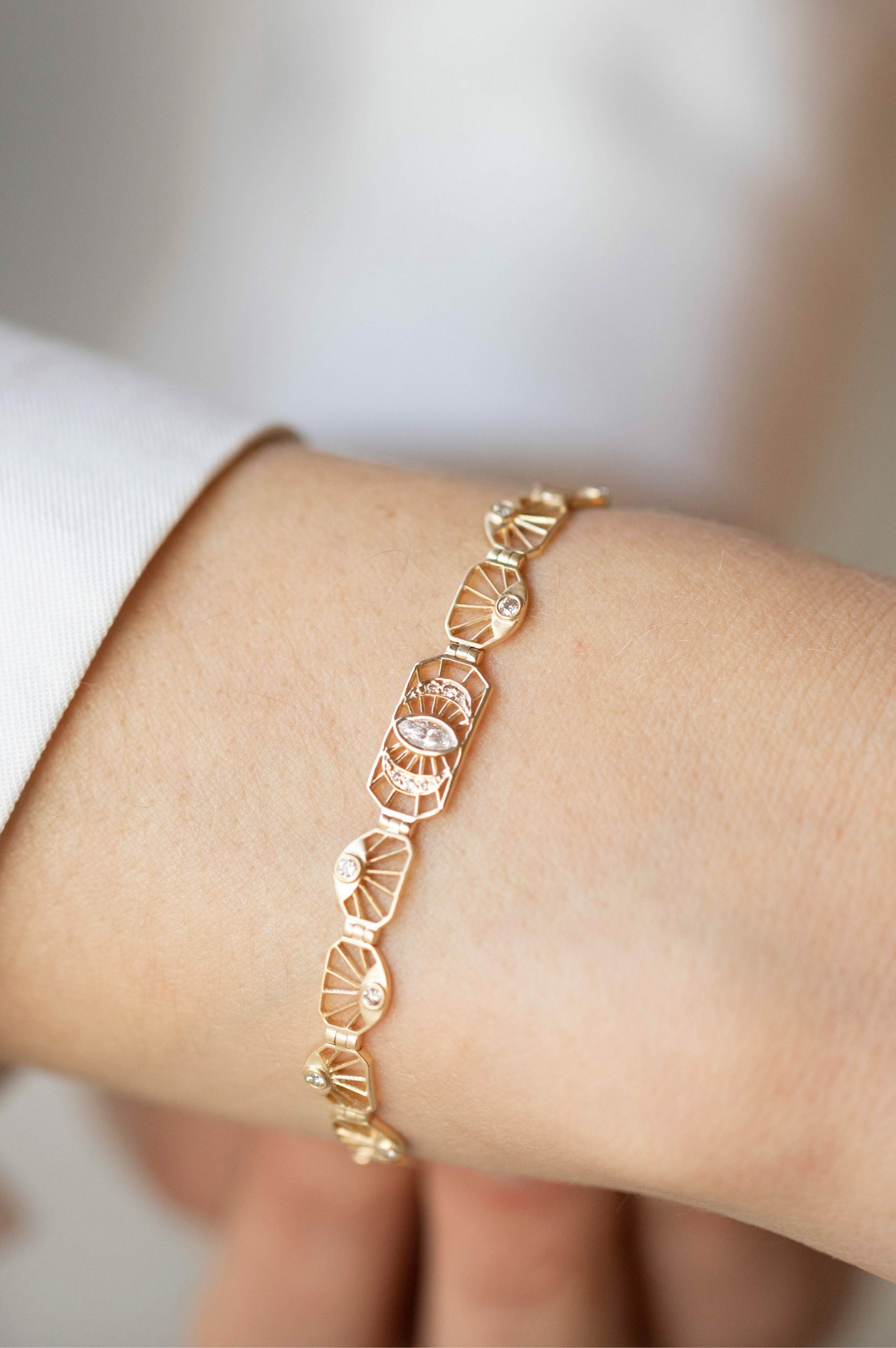 Yellow gold articulated bracelet diamond eye motif links worn on wrist Celine Daoust