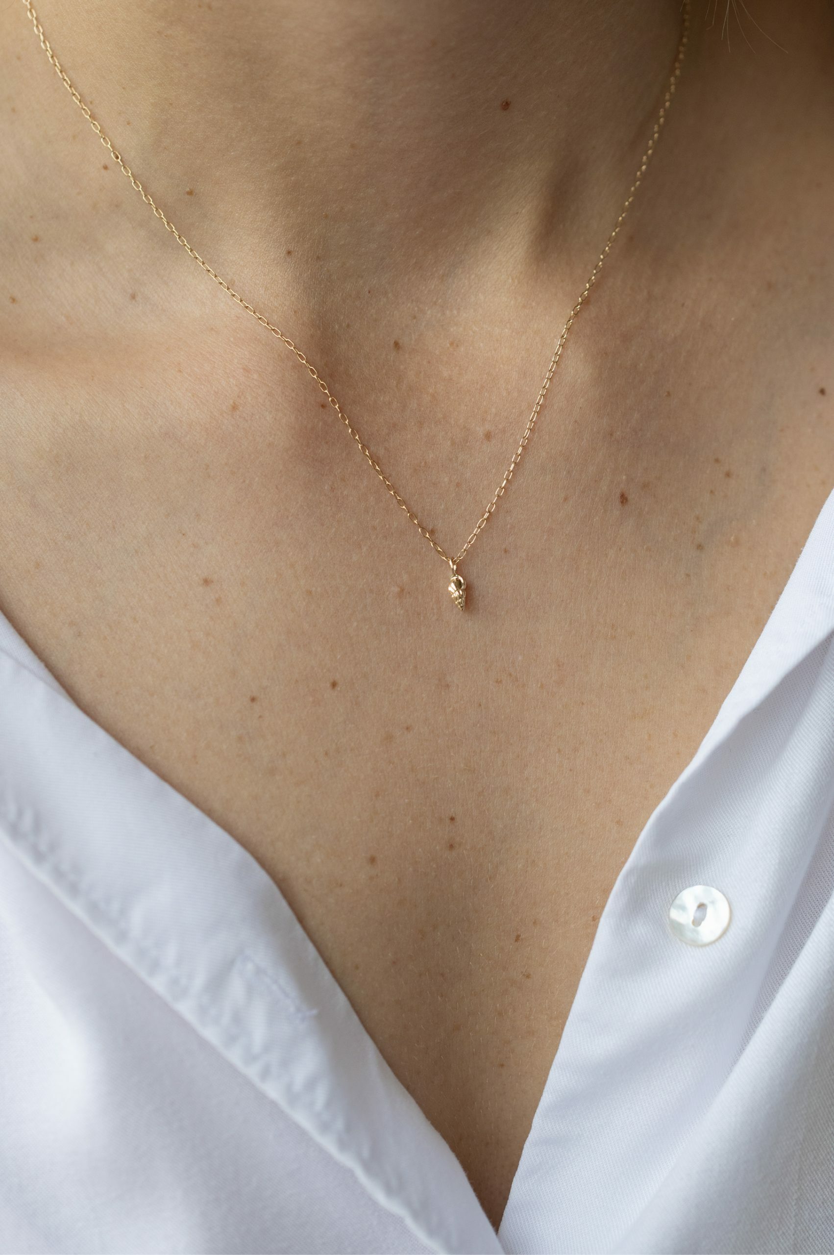 Yellow gold necklace small sculpted shell charm pendant delicate chain Celine Daoust