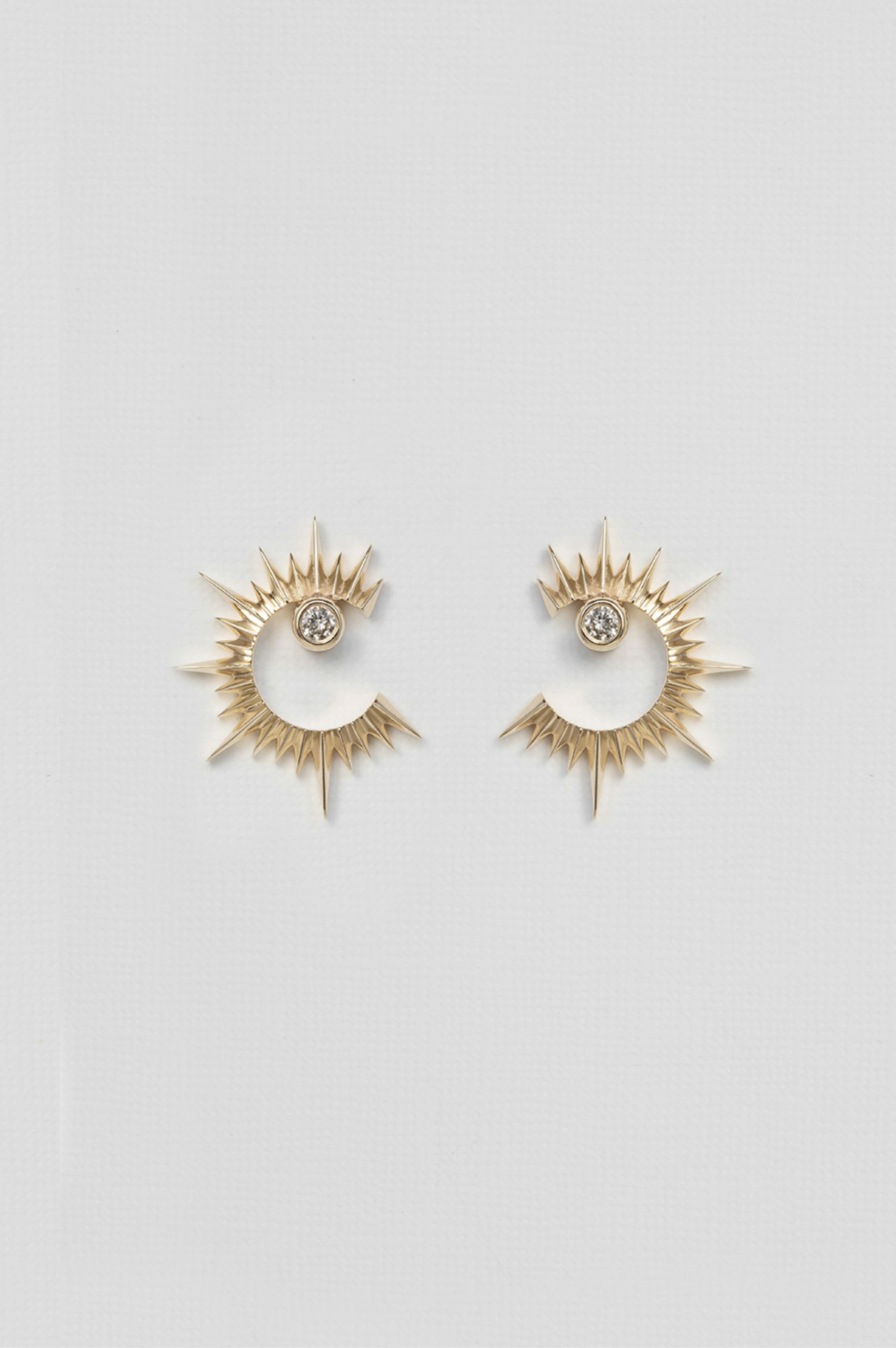 yellow gold statement earrings featuring a circular open sun shape with radiating spikes and a central diamond, creating a bold celestial silhouette