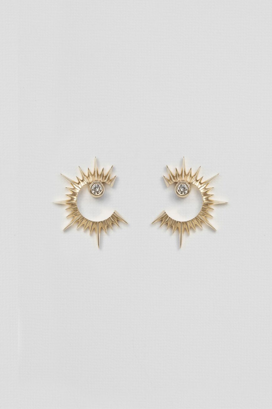 yellow gold statement earrings featuring a circular open sun shape with radiating spikes and a central diamond, creating a bold celestial silhouette