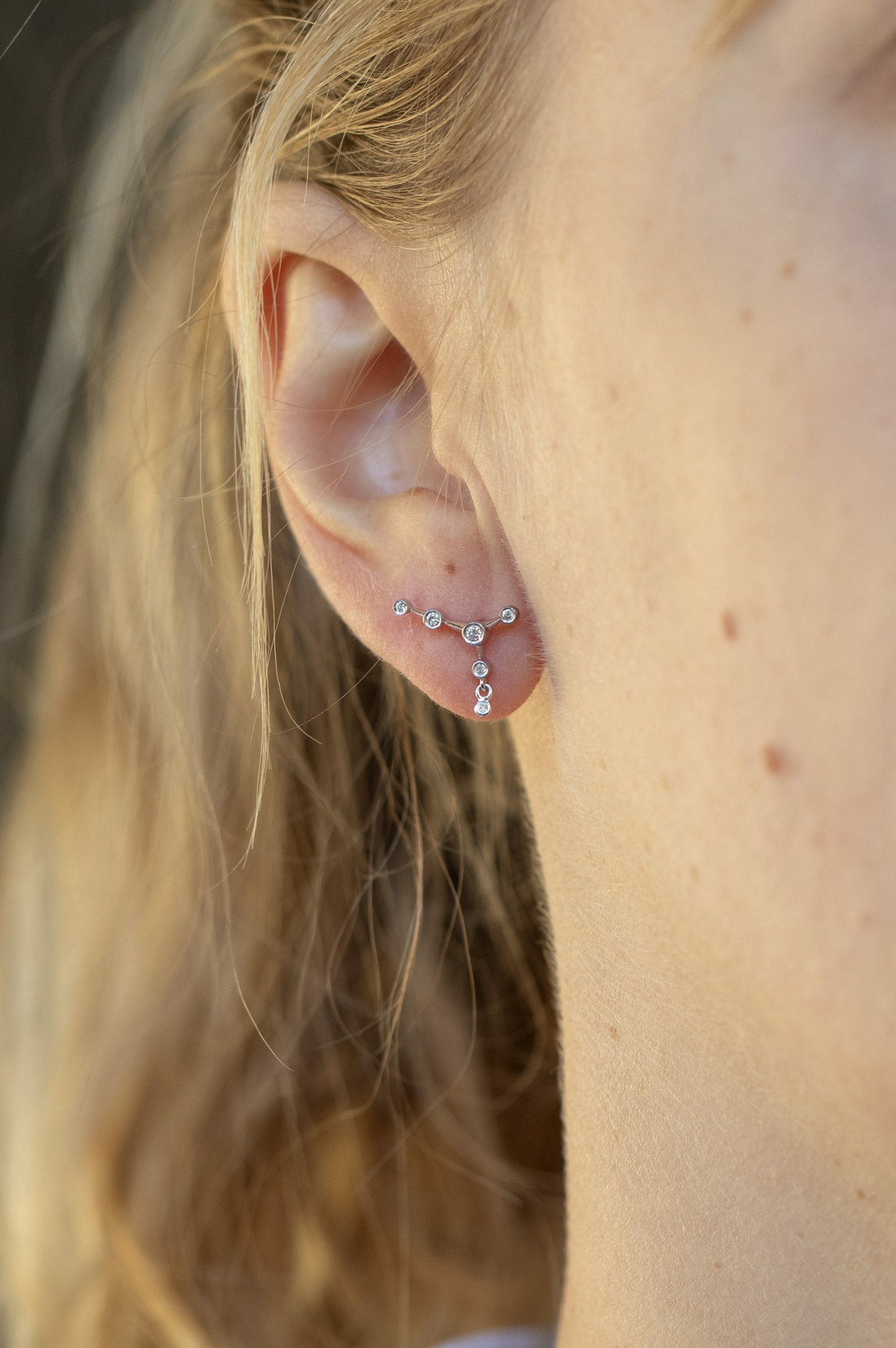 white gold ear jacket earrings featuring a constellation of diamonds along the lobe with a small dangling diamond drop below