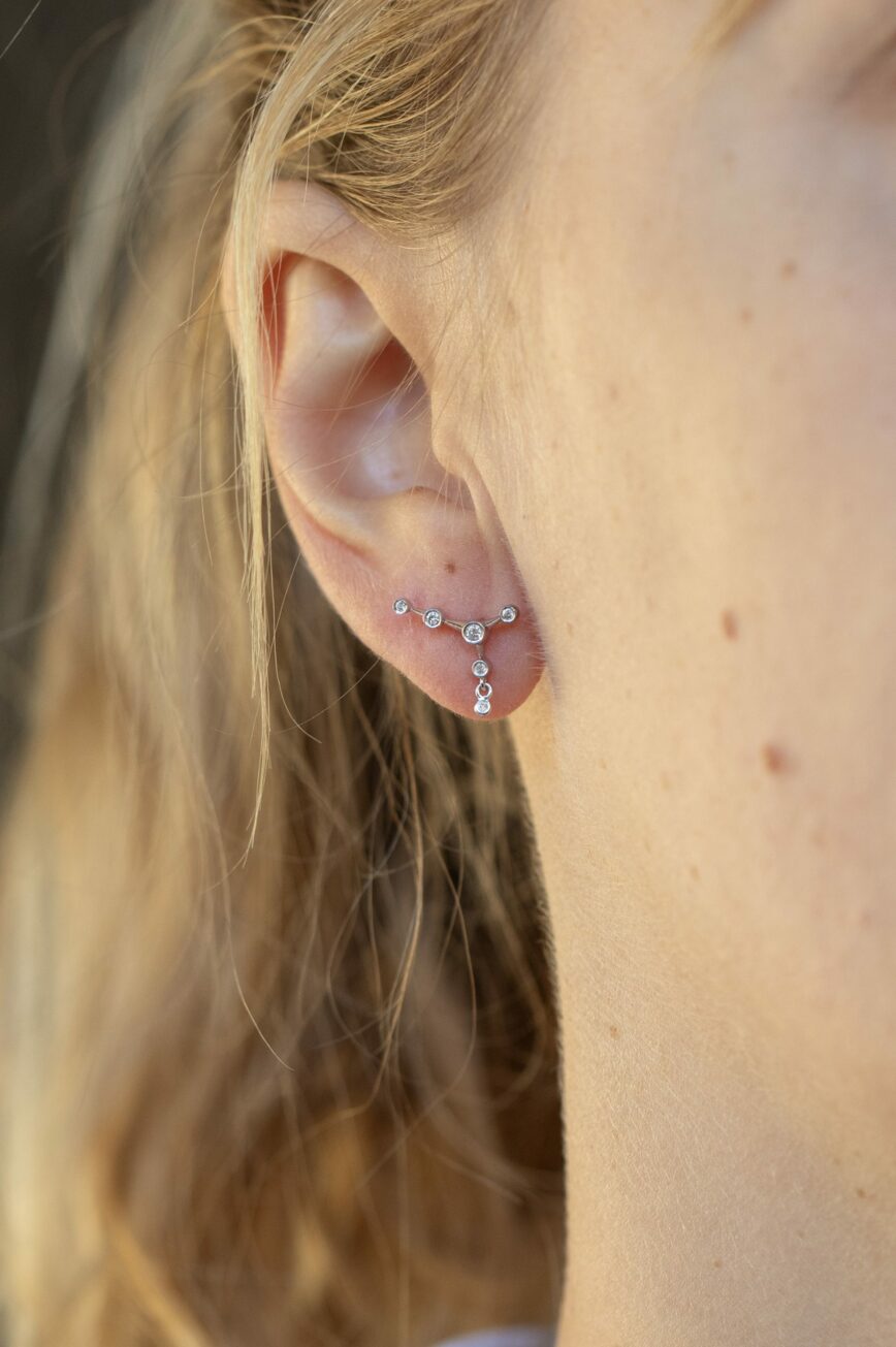 white gold ear jacket earrings featuring a constellation of diamonds along the lobe with a small dangling diamond drop below