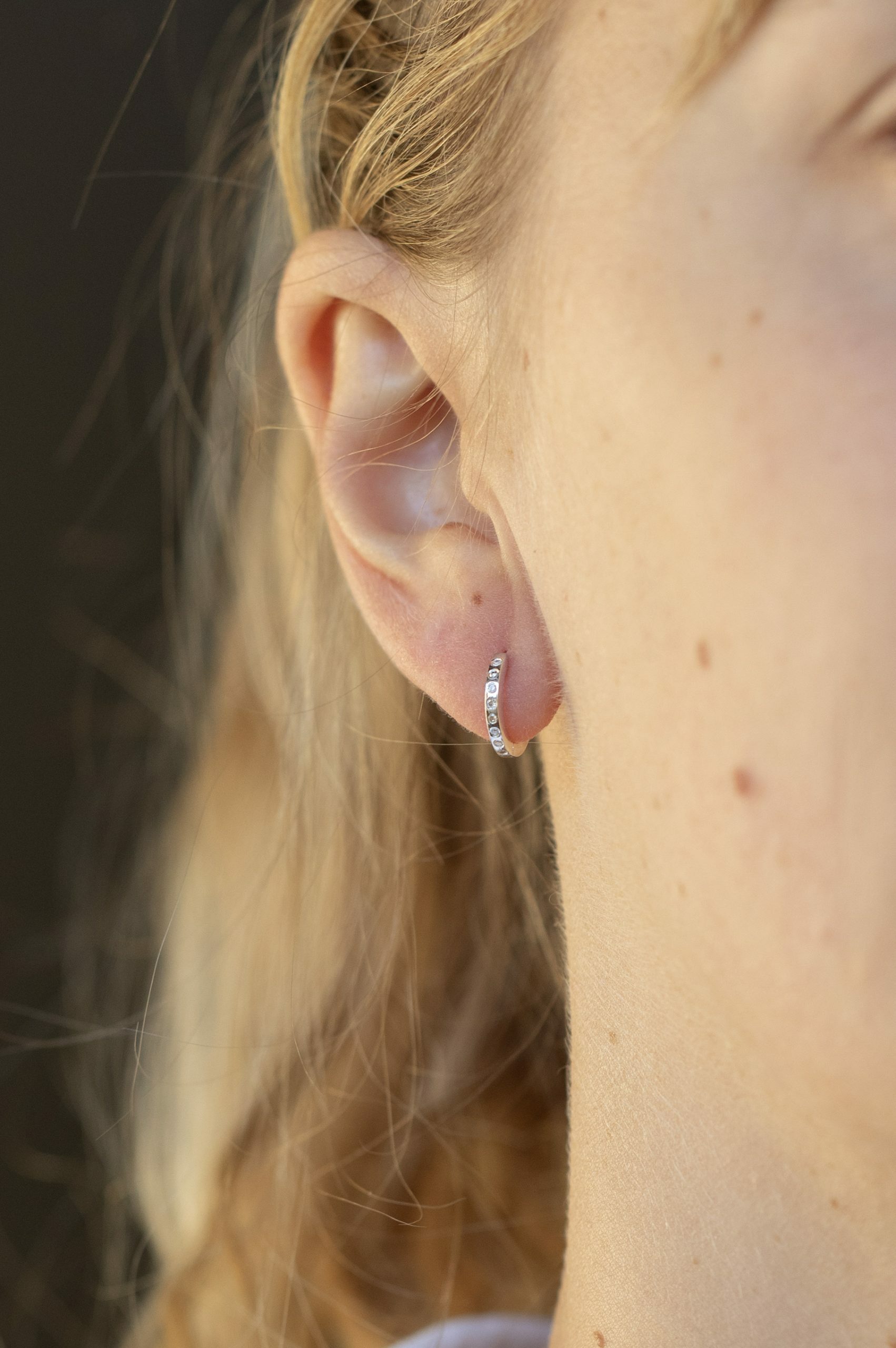 white gold small hoop earrings with a continuous pavé line of round brilliant diamonds along the front of the hoop