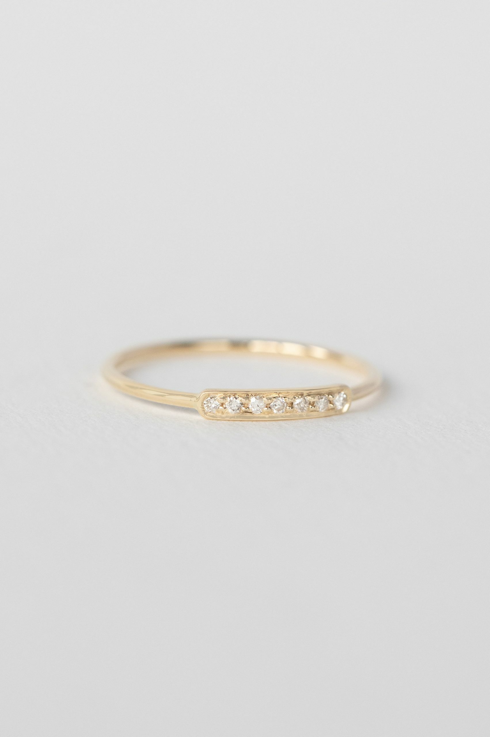 Yellow gold slim band ring multiple small bezel-set diamonds bar Celine Daoust