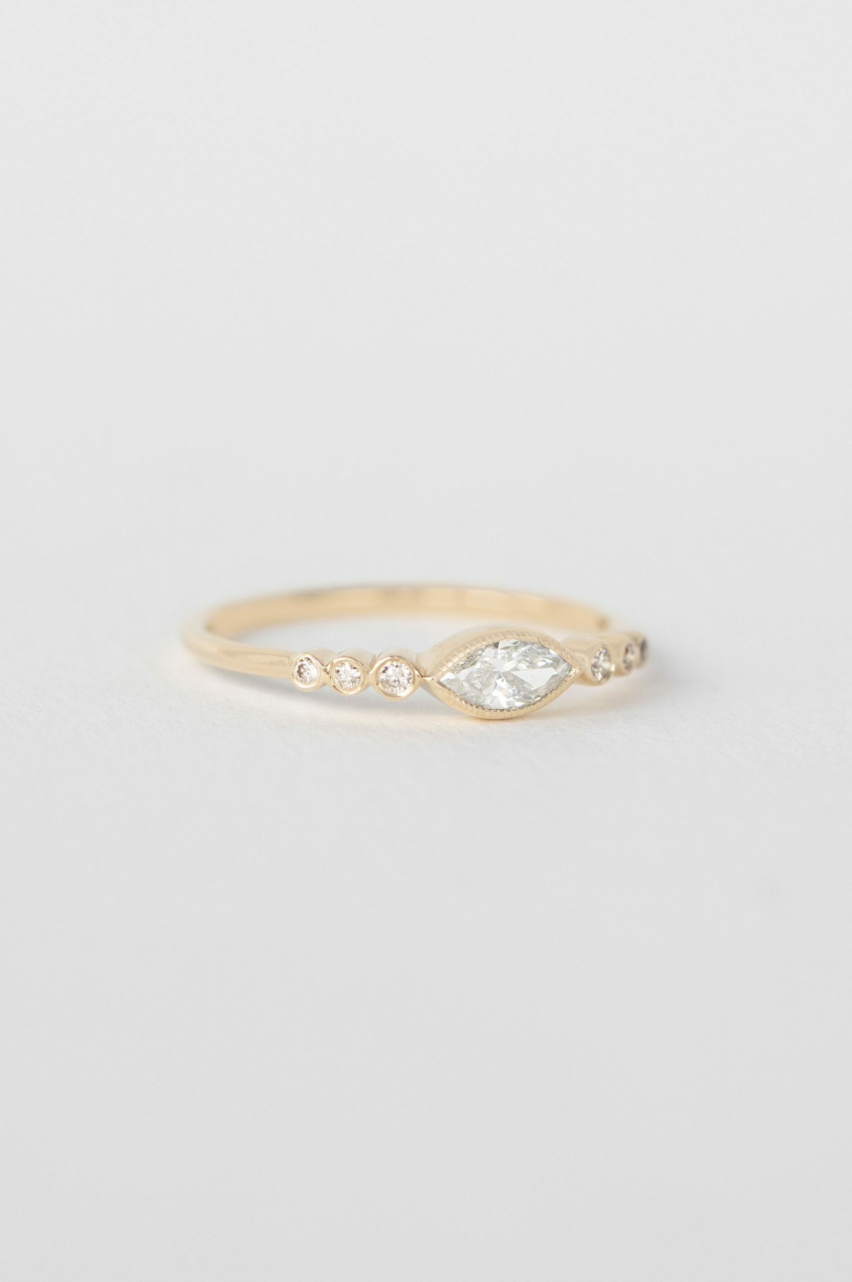 Yellow gold ring marquise diamond six bezel-set diamond accents slim band Celine Daoust
