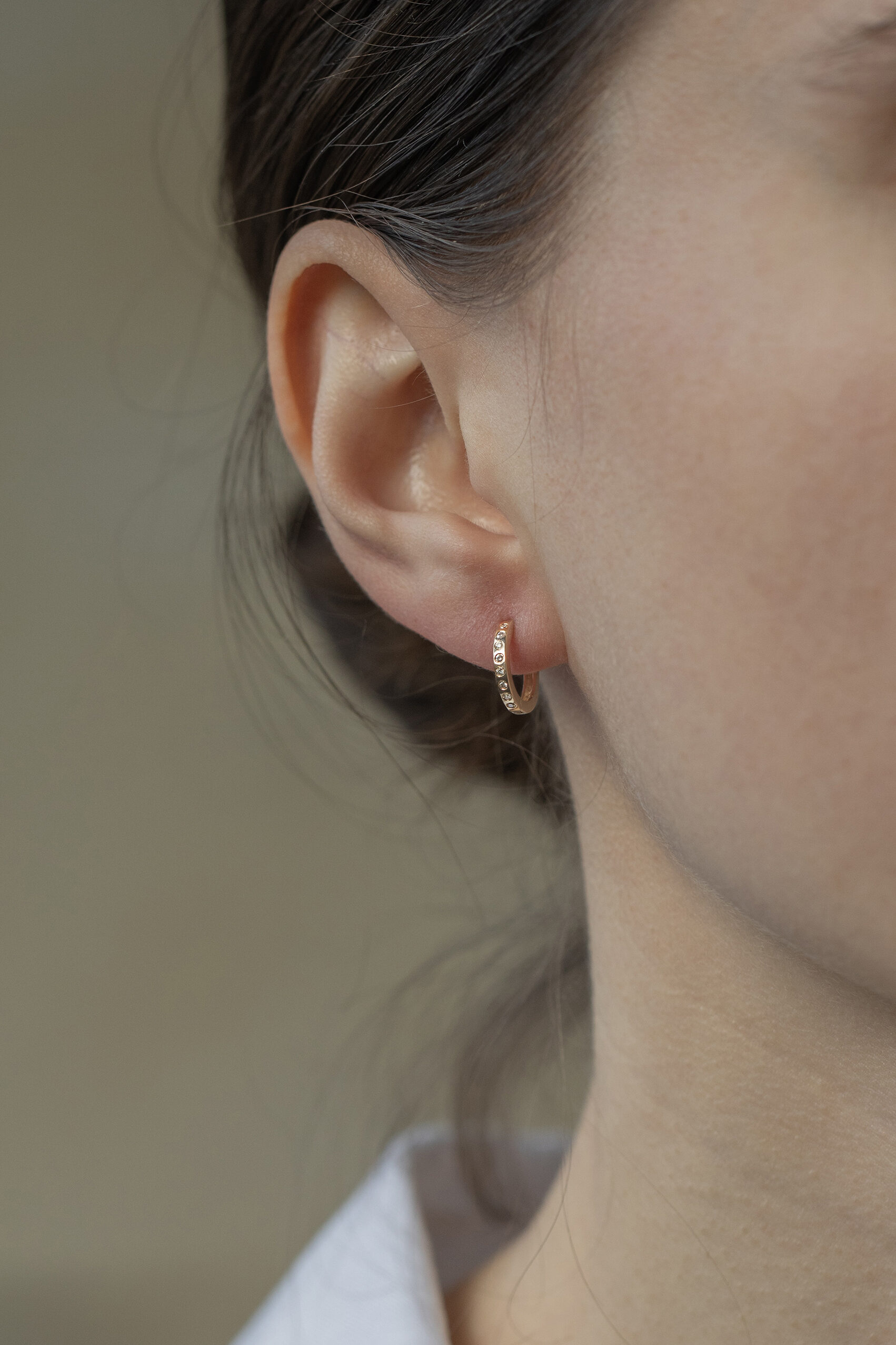 Yellow gold huggie hoop earrings pavé diamond accent worn on ear Celine Daoust
