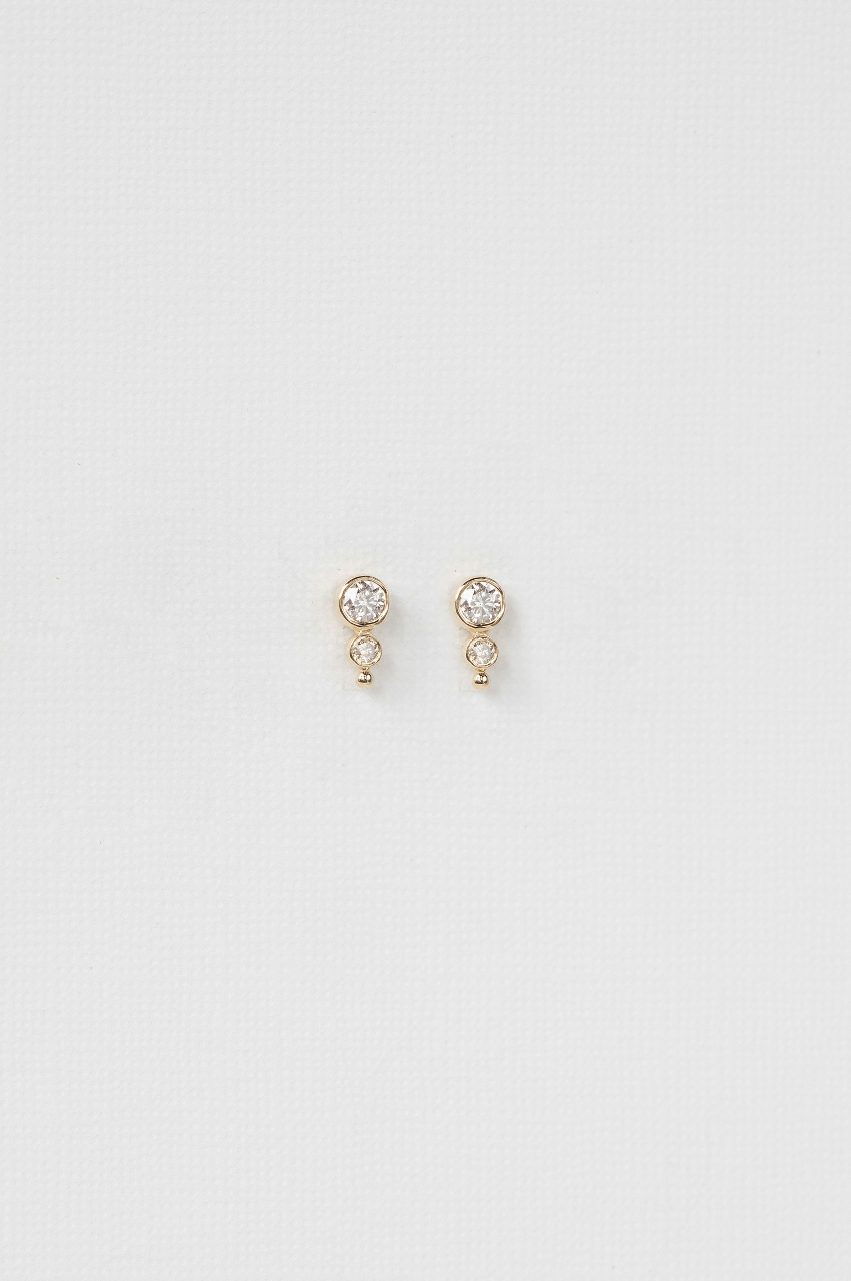 yellow gold drop earrings each with a bezel-set round diamond at top suspending a smaller diamond drop, simple and elegant