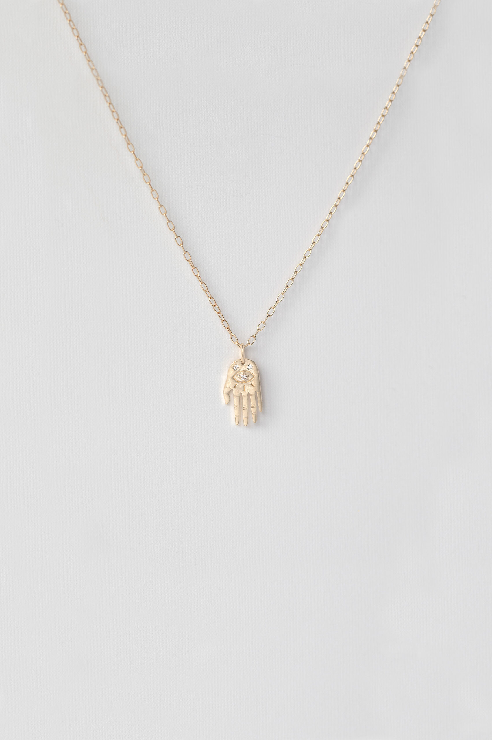 Yellow gold necklace small sculpted hand pendant diamond eye motif delicate chain Celine Daoust
