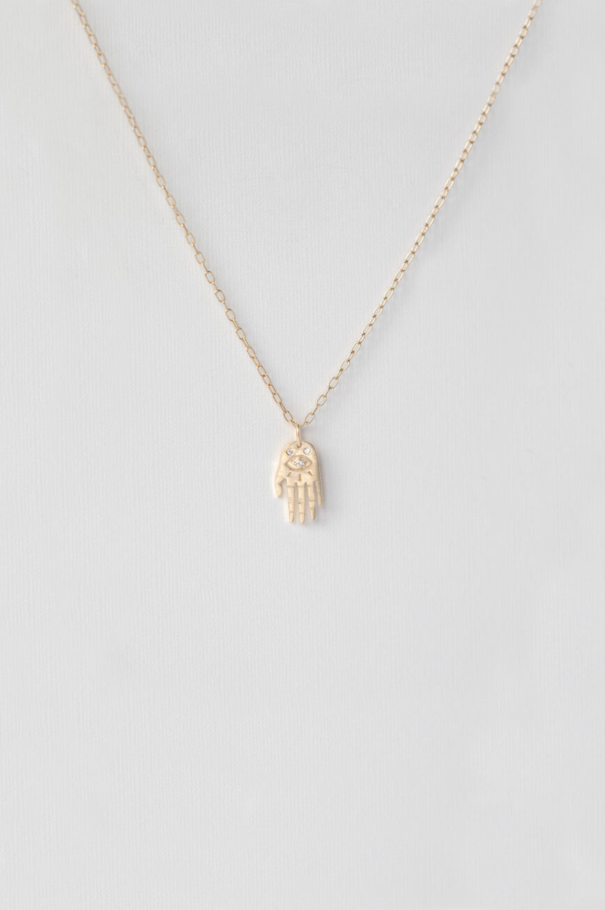 Yellow gold necklace small sculpted hand pendant diamond eye motif delicate chain Celine Daoust