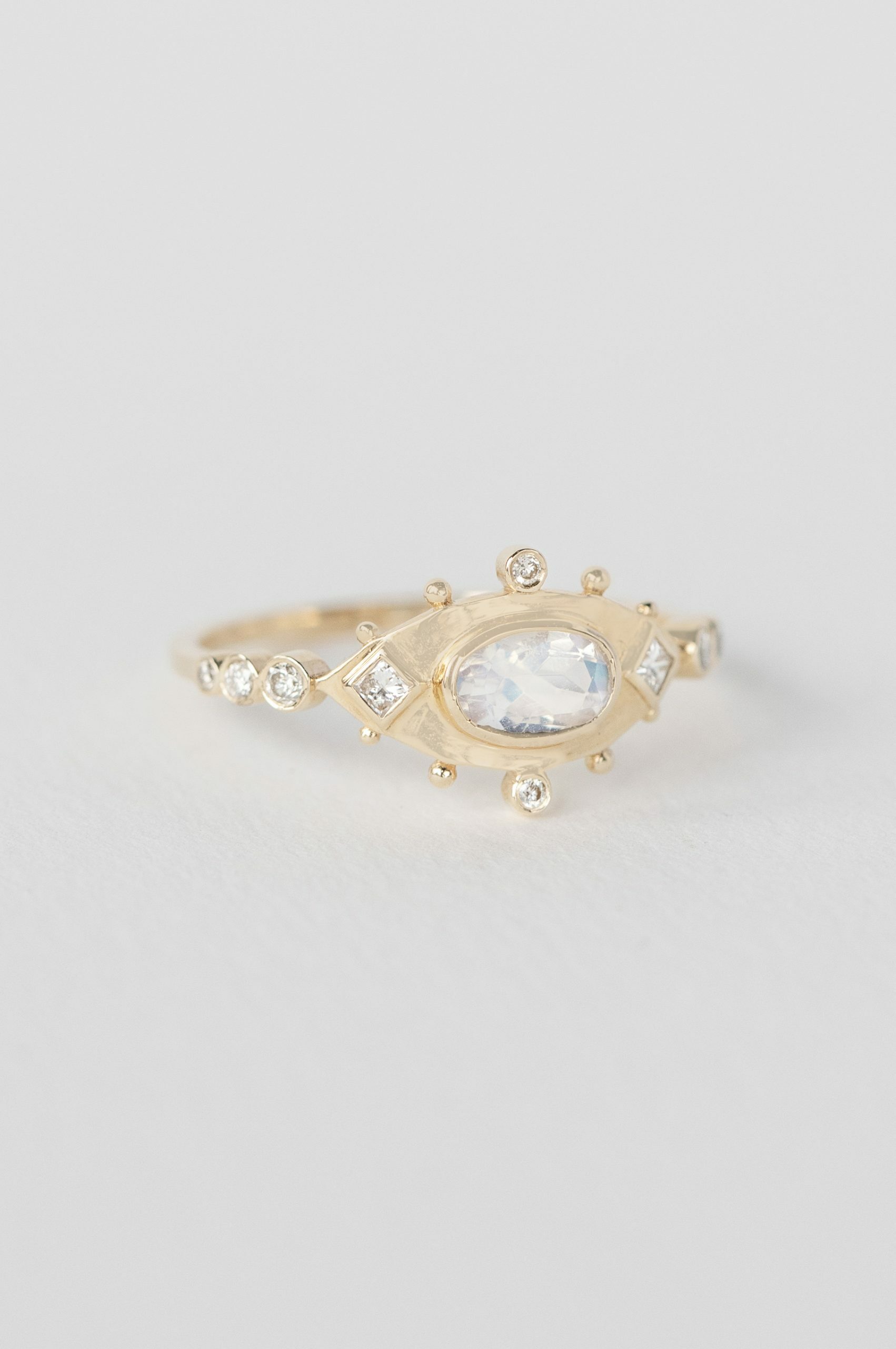 Yellow gold ring oval moonstone diamond accents eye motif band Celine Daoust