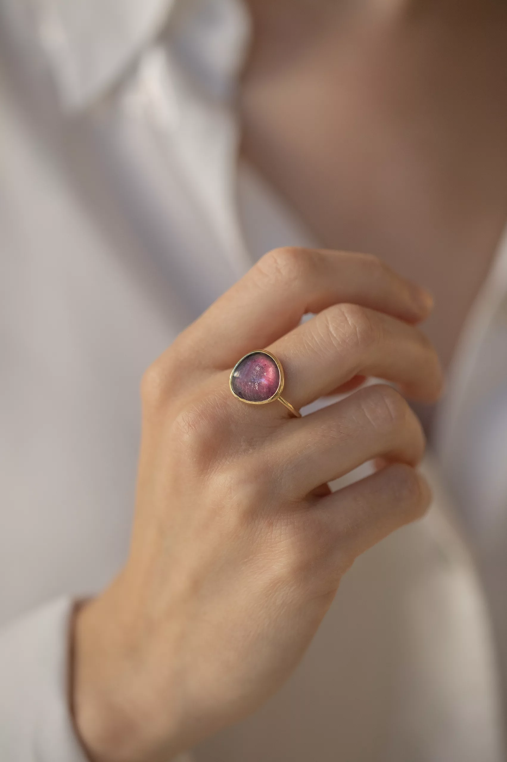 yellow gold ring with a large bezel-set slice of pink tourmaline, showcasing the stone's natural organic texture and deep magenta hues