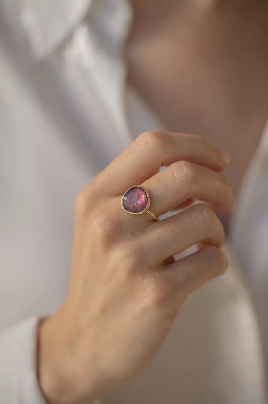 yellow gold ring with a large bezel-set slice of pink tourmaline, showcasing the stone's natural organic texture and deep magenta hues