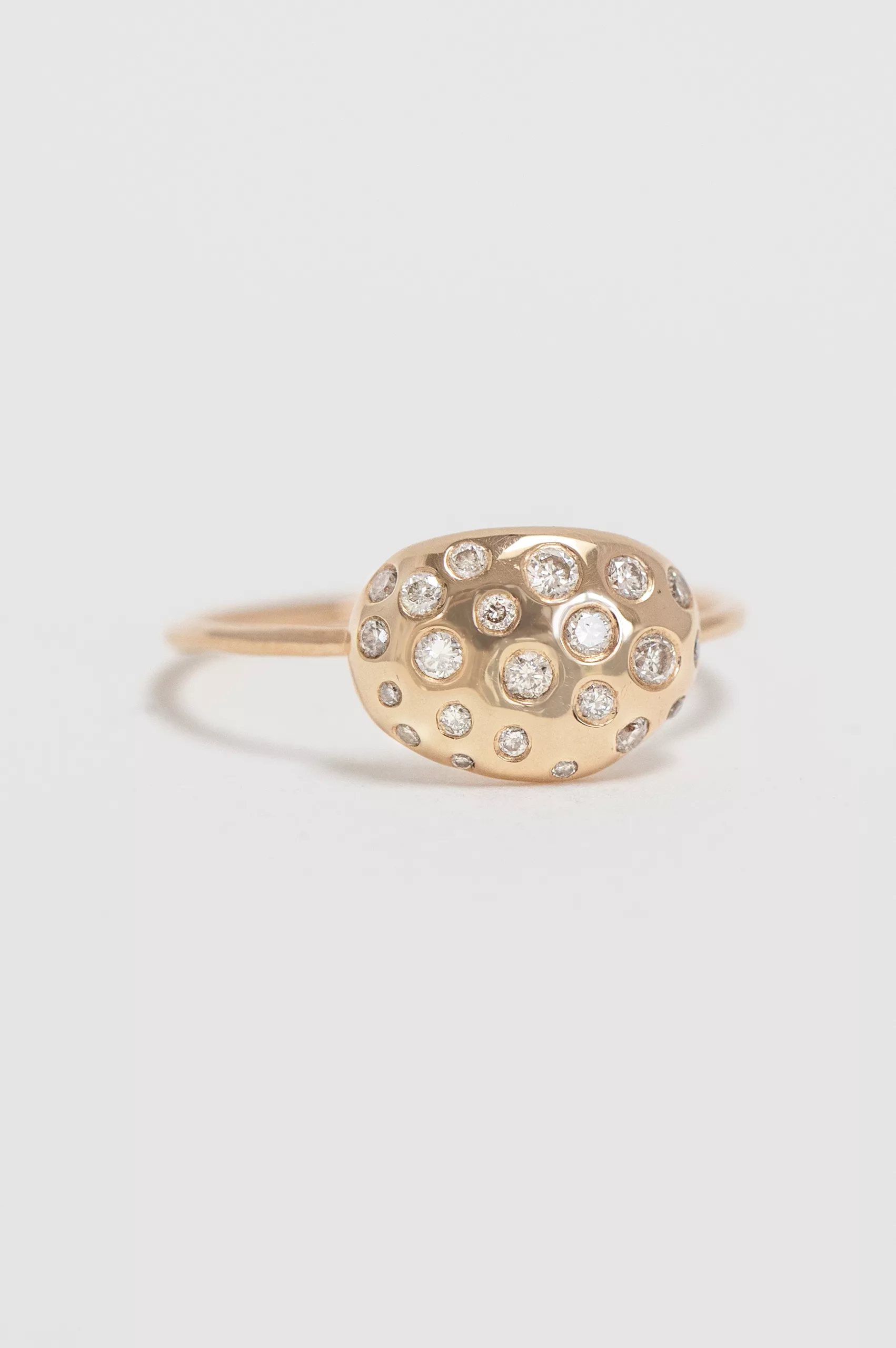 yellow gold ring with an oval dome-shaped shell motif pavé-set with round brilliant diamonds of varying sizes, mounted on a thin band