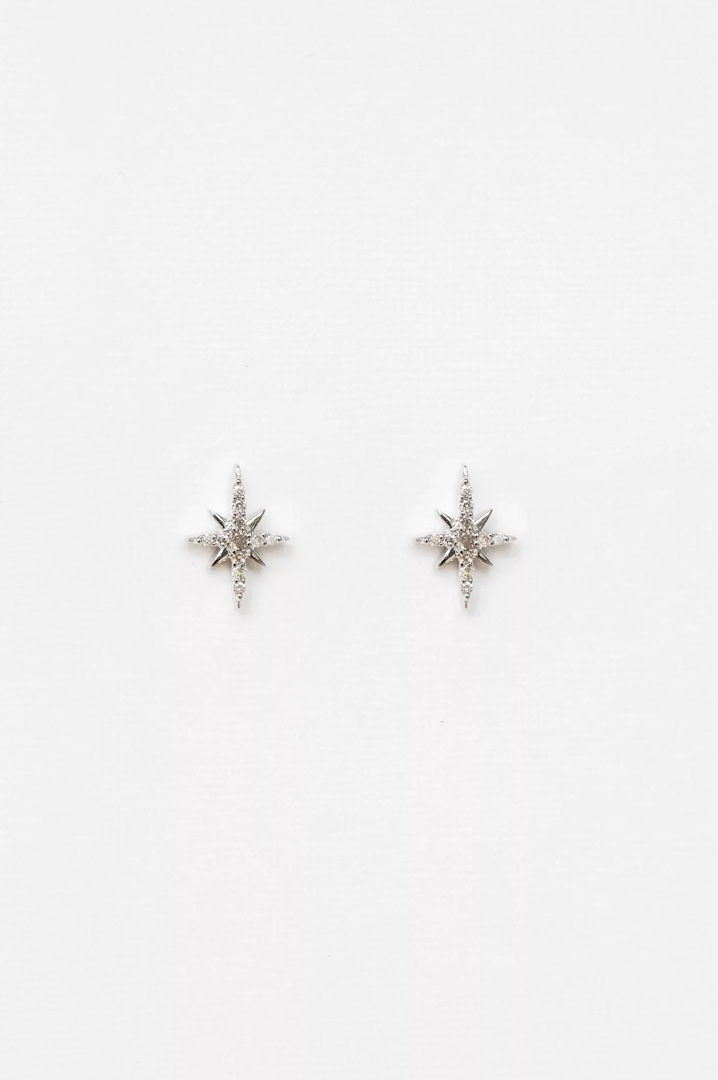 white gold stud earrings each featuring an eight-pointed north star pavé-set with round brilliant diamonds