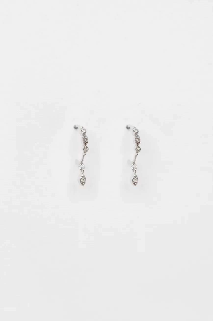white gold drop earrings each featuring a vertical cascade of three bezel-set diamonds with a smaller dangling diamond at the base