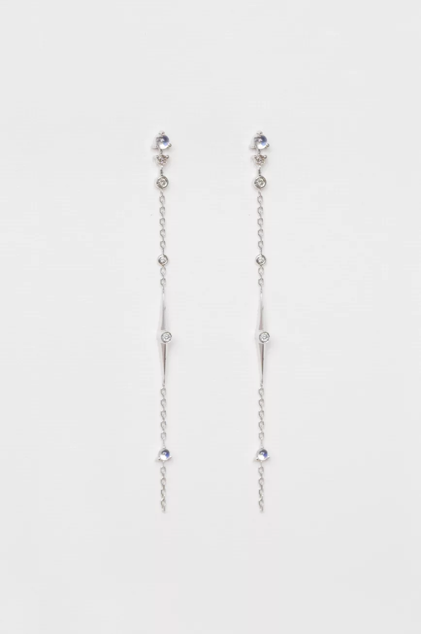 white gold long chain earrings each featuring a moonstone and diamond chain drop with dangling geometric details, worn as a delicate ear crawler